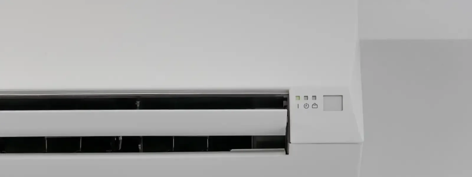 Unidad de aire acondicionado blanca sobre una pared blanca.