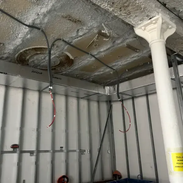 Interior de obra en construcción; estructura metálica en paredes y techo; conducto eléctrico expuesto.