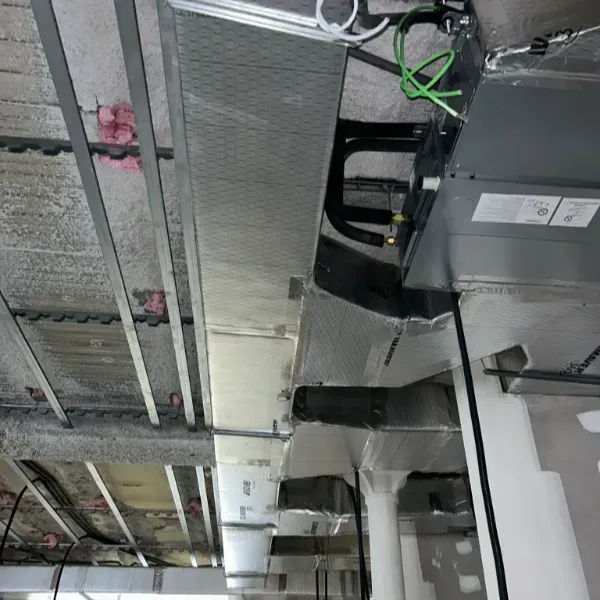 Vista interior del techo comercial con sistema de climatización, conductos y aislamiento visibles. Construcción en curso.