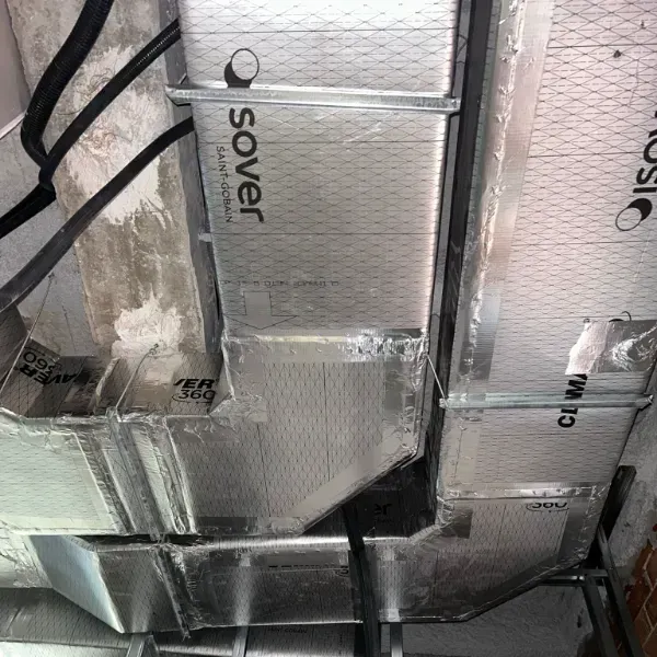 Conductos HVAC aislados, plateados con marca, instalados en un techo.