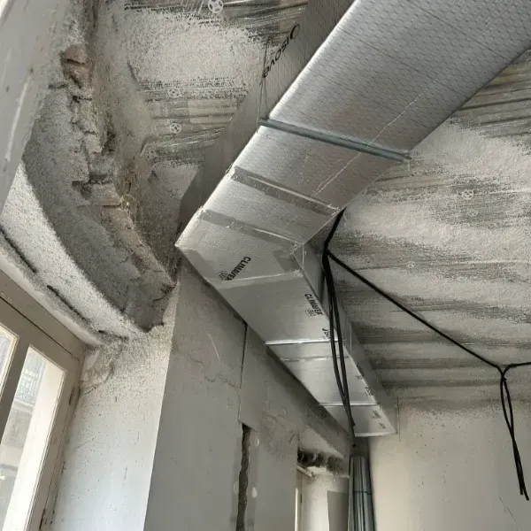 Instalación de conductos de aire en local en construcción con techo y paredes de hormigón.