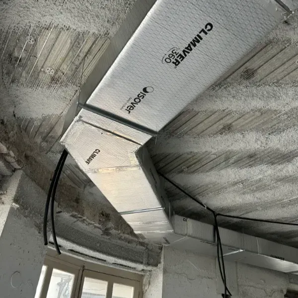 Conductos HVAC aislados instalados en un techo de concreto con etiquetado de marca visible.