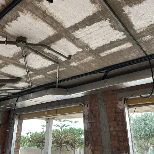 Conductos eléctricos y caja de conexiones instalados en un techo de hormigón de un edificio en construcción.
