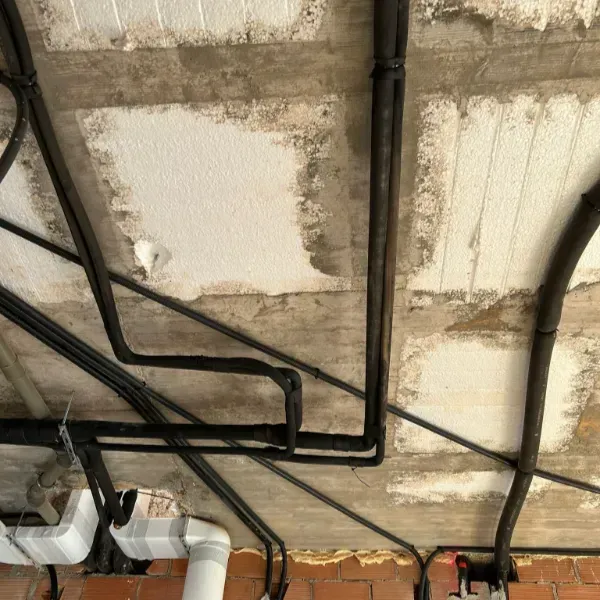 Un conducto y cableado de color negro corren a través de un techo de hormigón teñido.