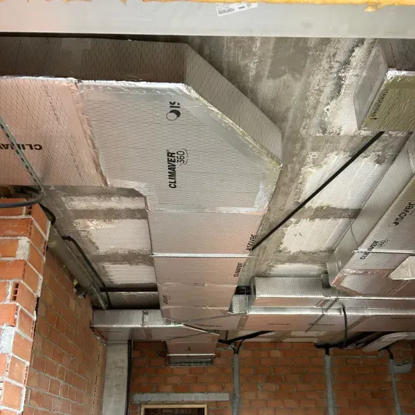 Material aislante instalado en un techo durante la construcción, con ladrillos a la vista y vigas de hormigón.