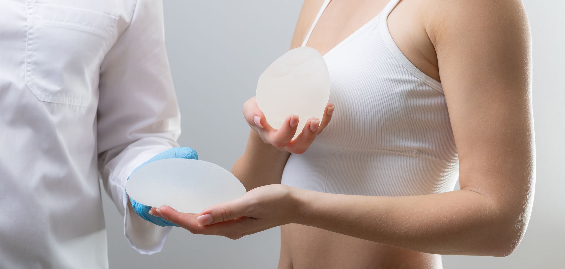 Une femme tient un implant mammaire, un médecin en blouse médicale tient un implant mammaire.
