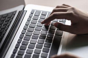 Eine Person tippt auf einem Laptop.