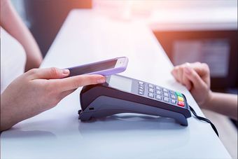 Eine Person benutzt eine Kreditkarte zum Bezahlen mit einem Mobiltelefon.