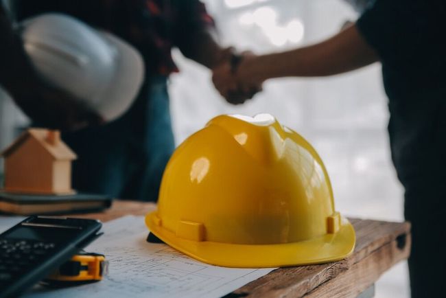Un casco amarillo está sobre una mesa de madera.