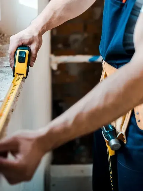 Un hombre está midiendo un trozo de madera con una cinta métrica.