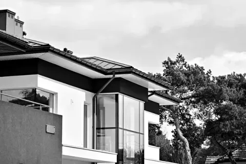 Una foto en blanco y negro de una casa con árboles al fondo.