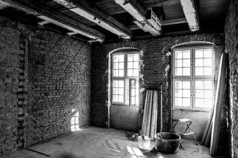 Una fotografía en blanco y negro de una habitación vacía con paredes de ladrillo y ventanas.