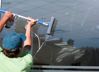 Un hombre está limpiando una ventana con una escobilla de goma.