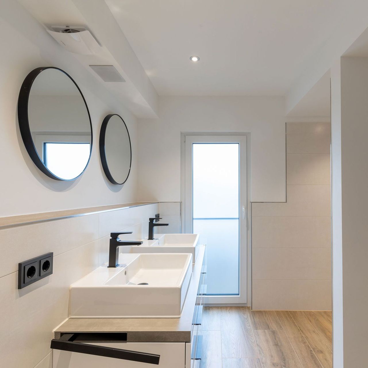 Ein Badezimmer mit zwei Waschbecken und zwei Spiegeln an der Wand