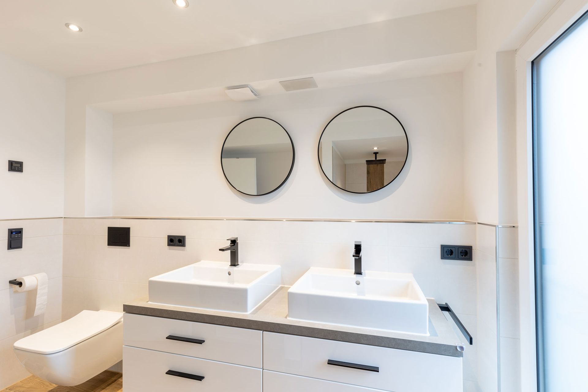 Ein Badezimmer mit zwei Waschbecken und zwei Spiegeln an der Wand