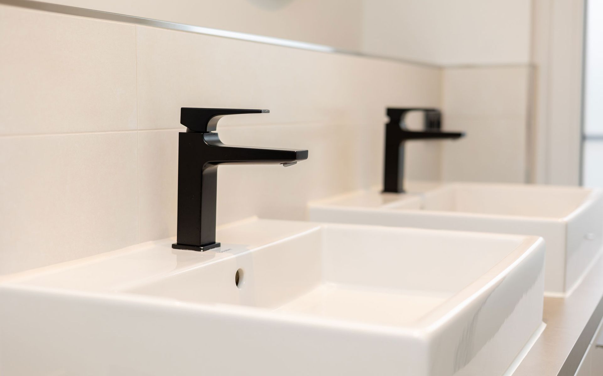 Ein Badezimmer mit zwei Waschbecken und zwei Spiegeln an der Wand