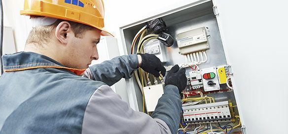 Un hombre con casco está trabajando en una caja eléctrica.