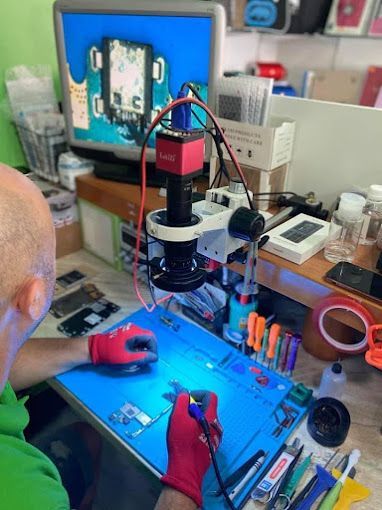 Un hombre está trabajando en un teléfono celular bajo un microscopio.
