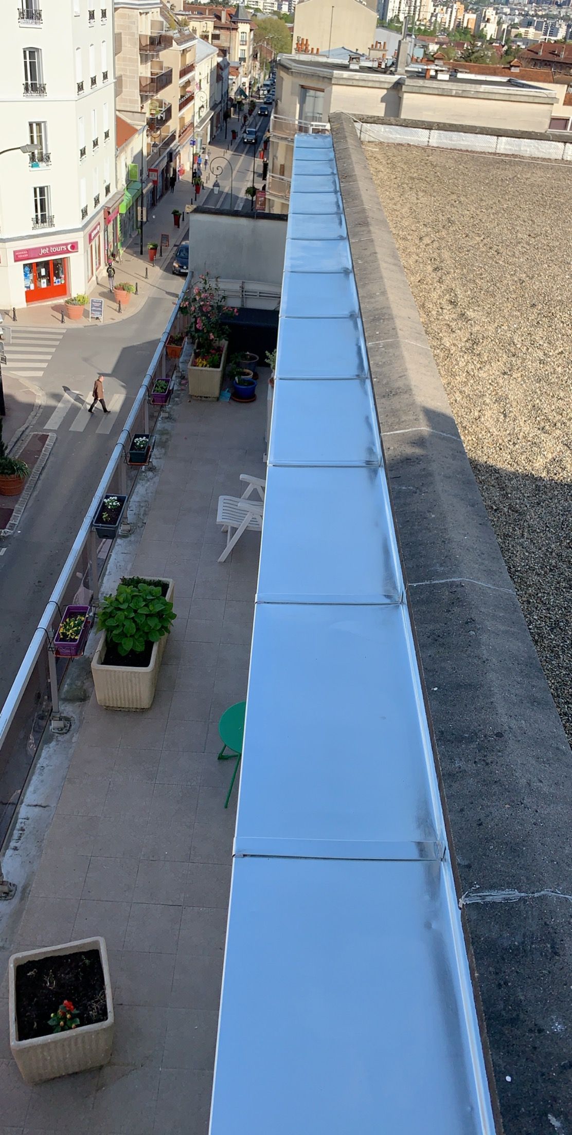 Vue depuis un toit donnant sur une rue de la ville avec des immeubles et des piétons.