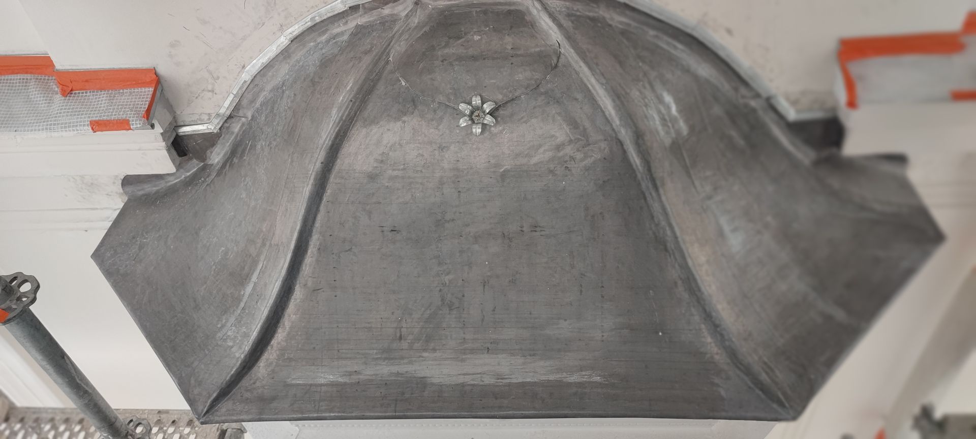 Un élément architectural en béton gris orné d'un motif floral est fixé au plafond.