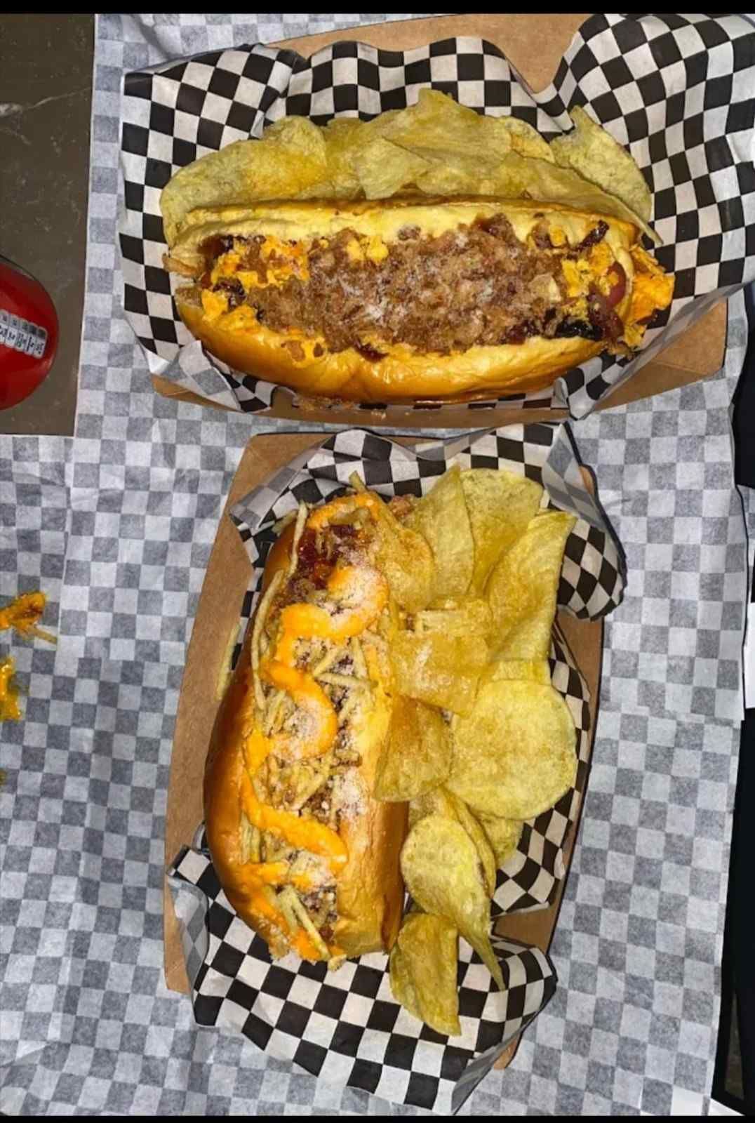 Dos sándwiches cargados con patatas fritas en cestas forradas con papel a cuadros