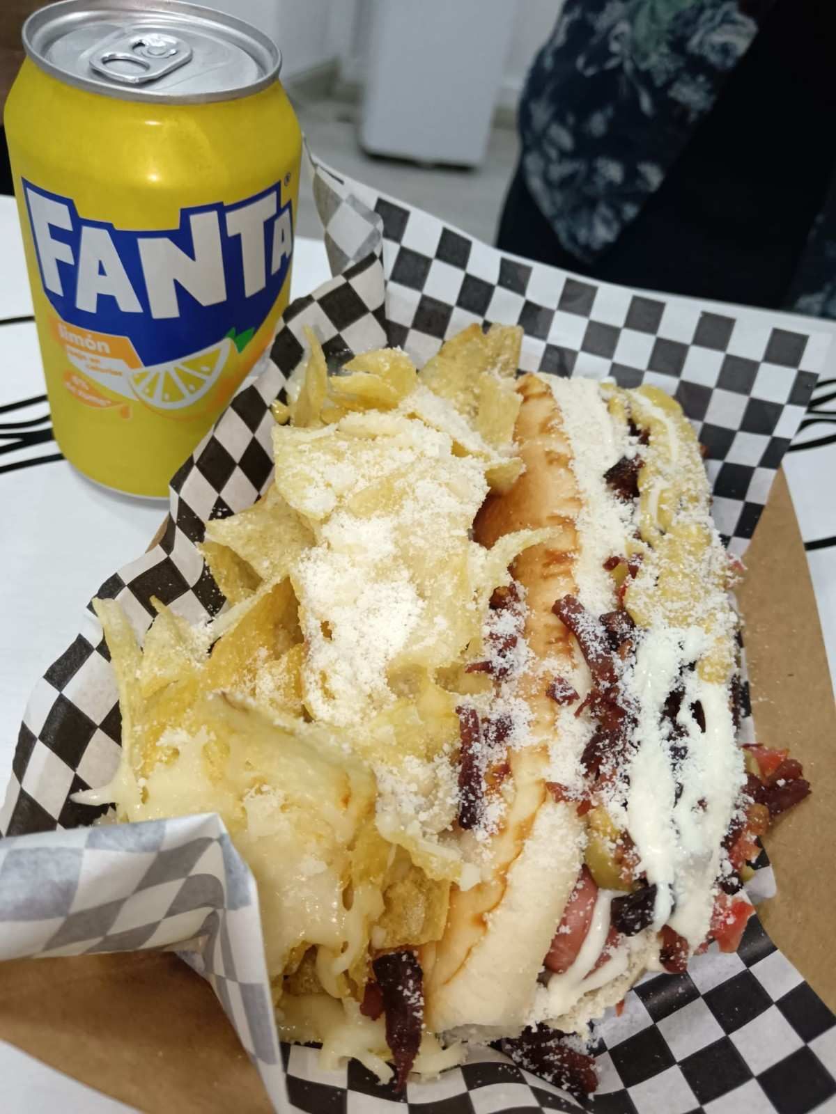 Lata de Fanta de limón, sándwich con patatas fritas en cesta.