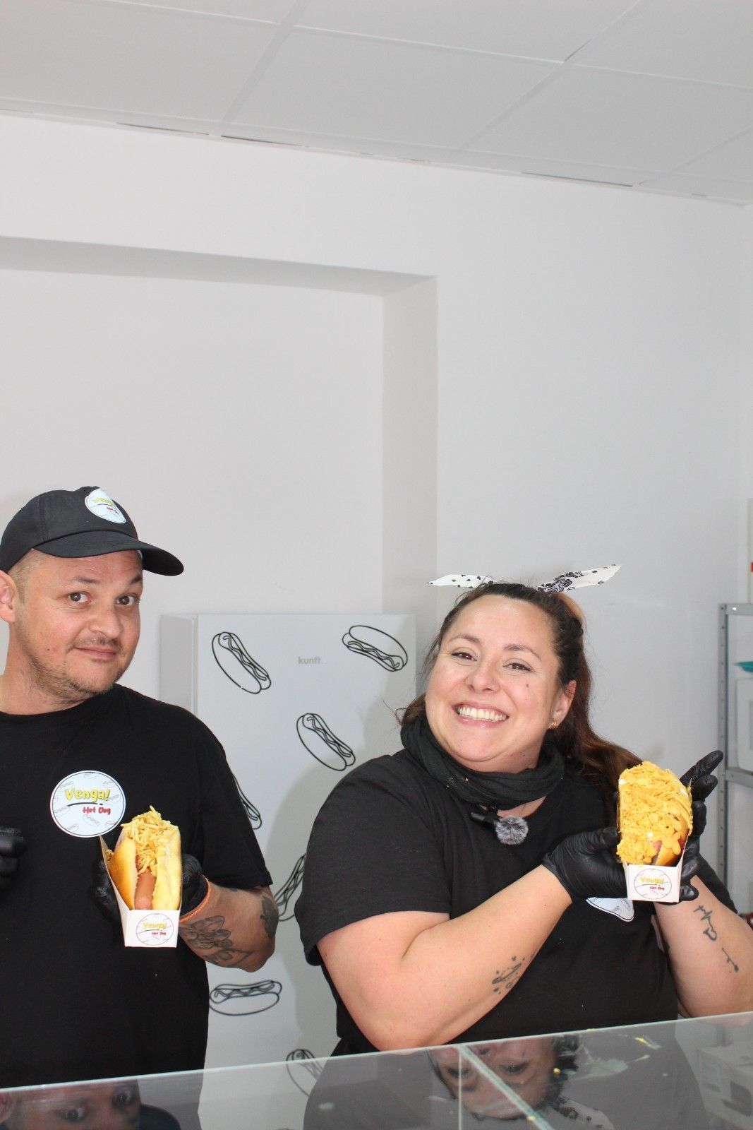 Dos personas sostienen alimentos con sonrisas, en un entorno de servicio de comidas.