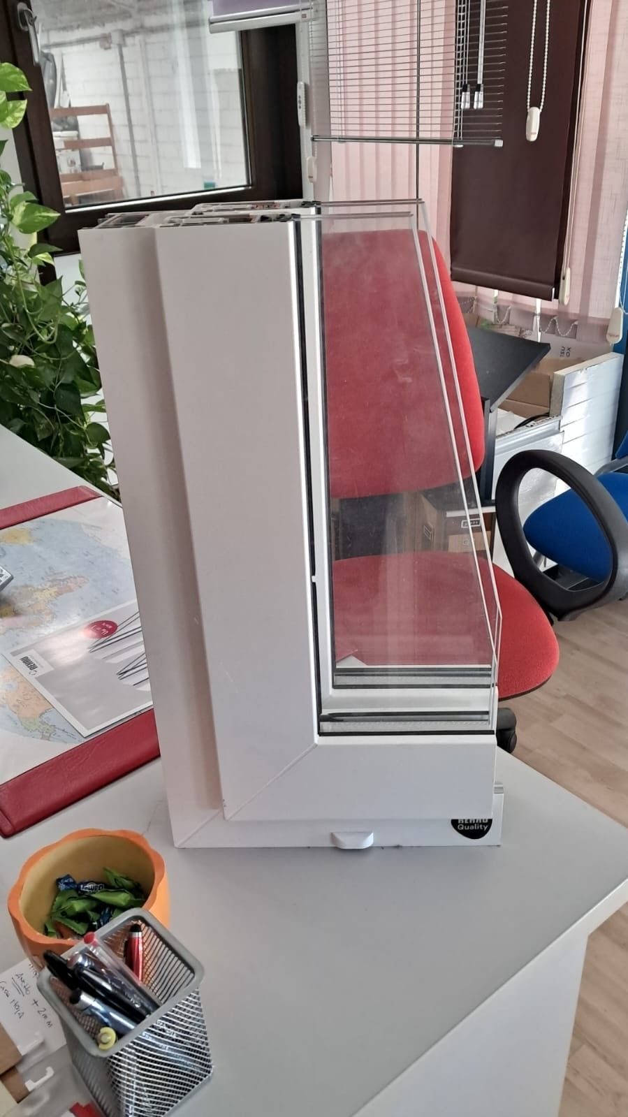 Electrodoméstico blanco con panel interior rojo sobre una mesa junto a ollas y utensilios pequeños.