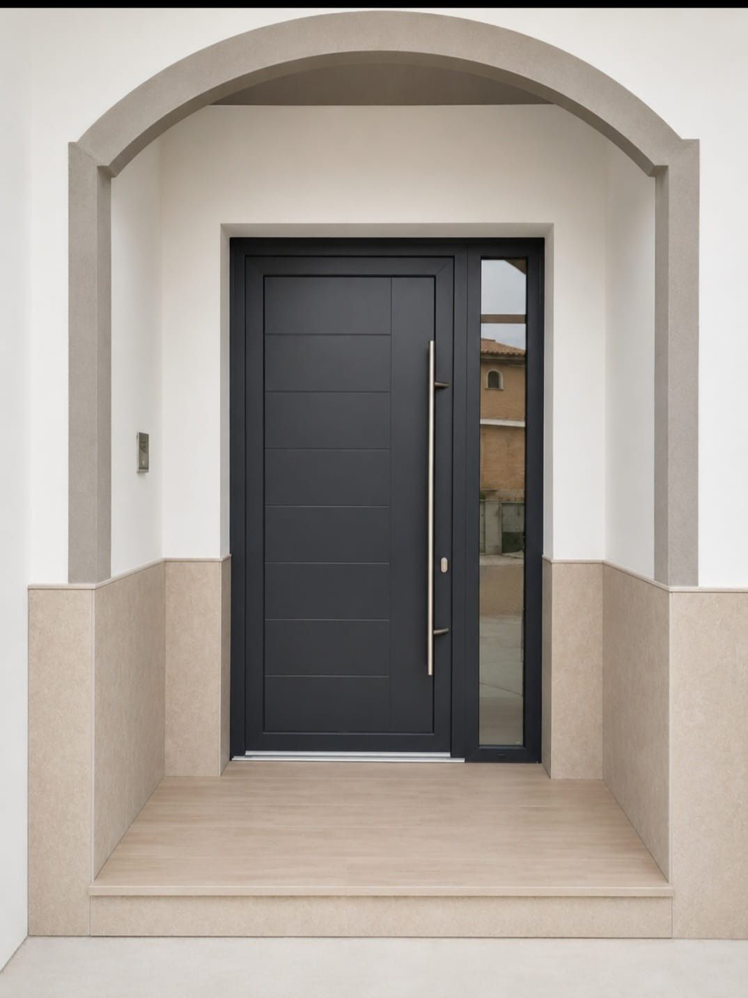 Entrada principal con puerta gris oscuro, marco arqueado beige y escalones de piedra clara.