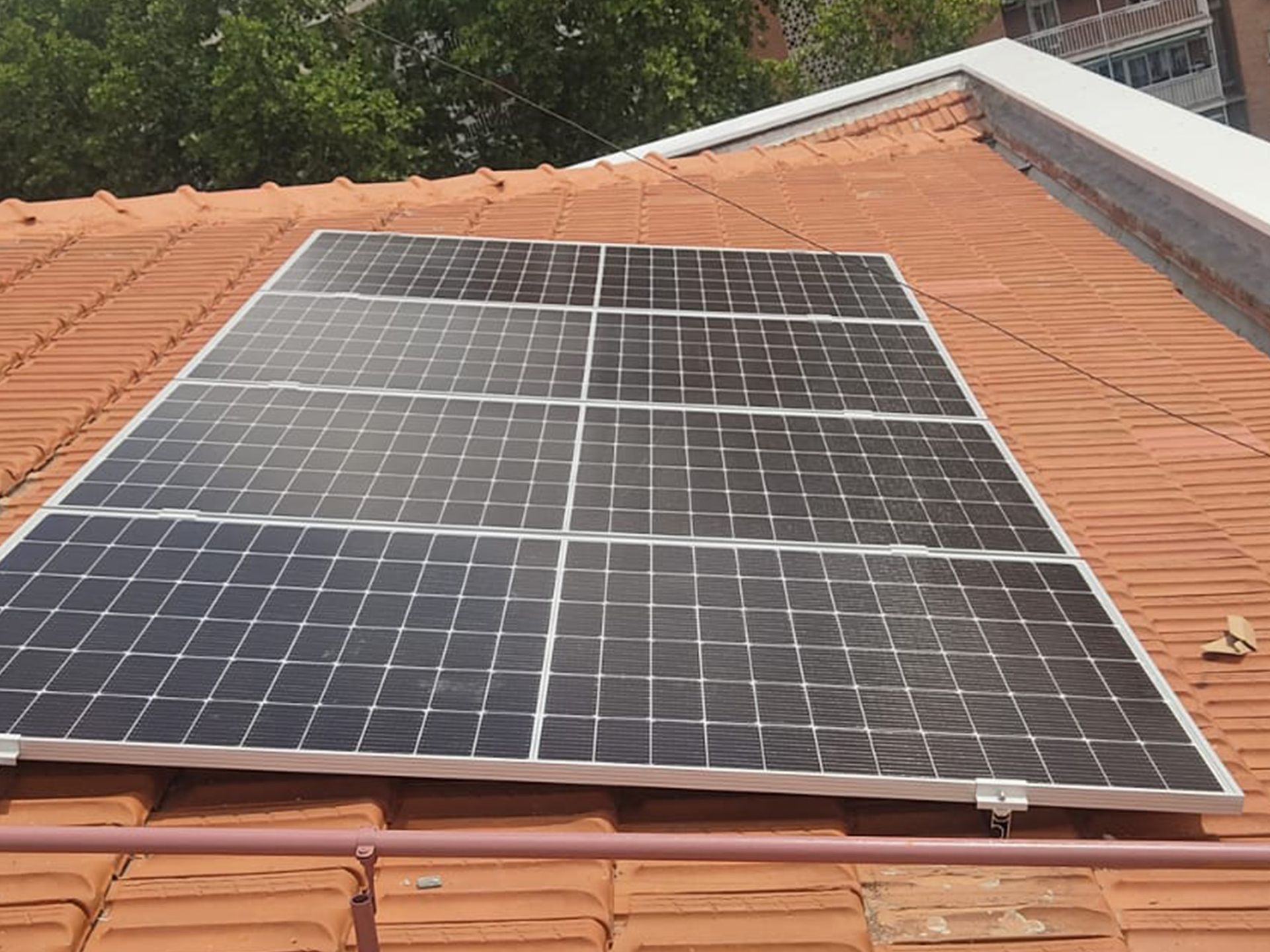 Una fila de paneles solares están colocados encima de un techo de tejas.