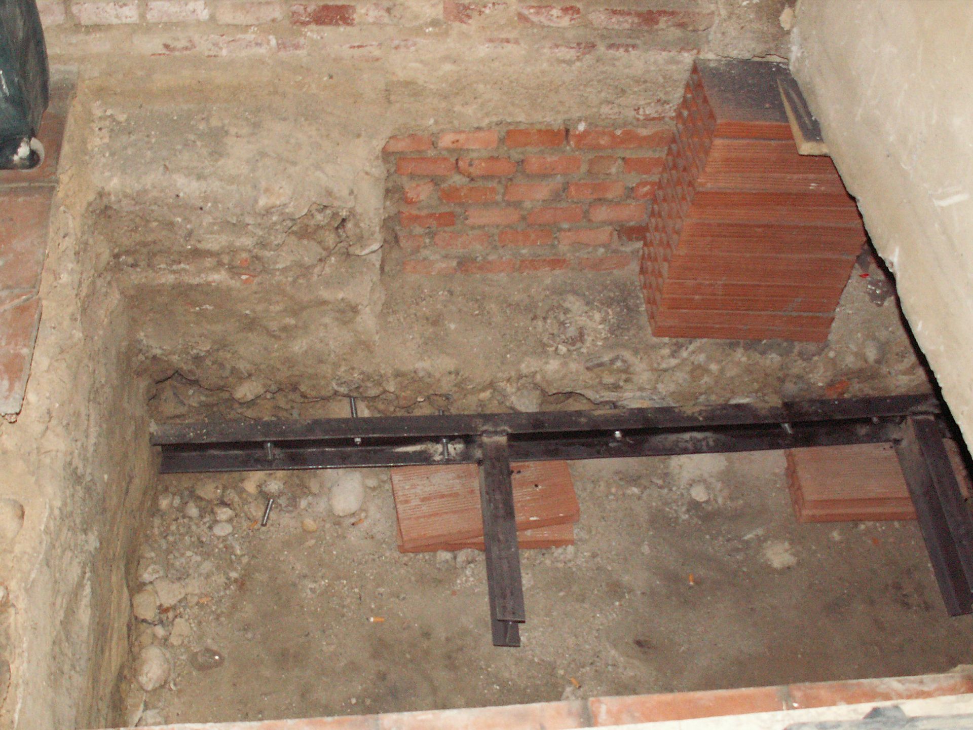 Un agujero en el suelo con una pared de ladrillos al fondo.