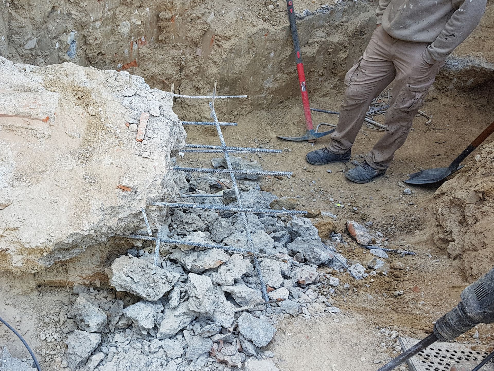 Un hombre está parado en un agujero con una pala y un martillo.