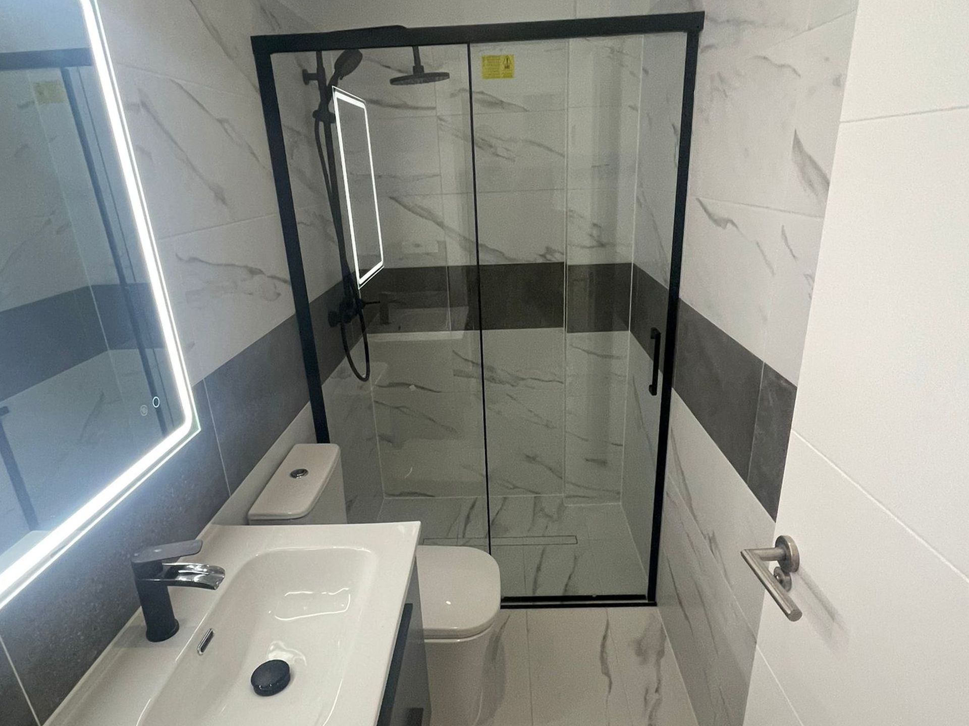 Un baño con lavabo, inodoro, ducha y espejo.
