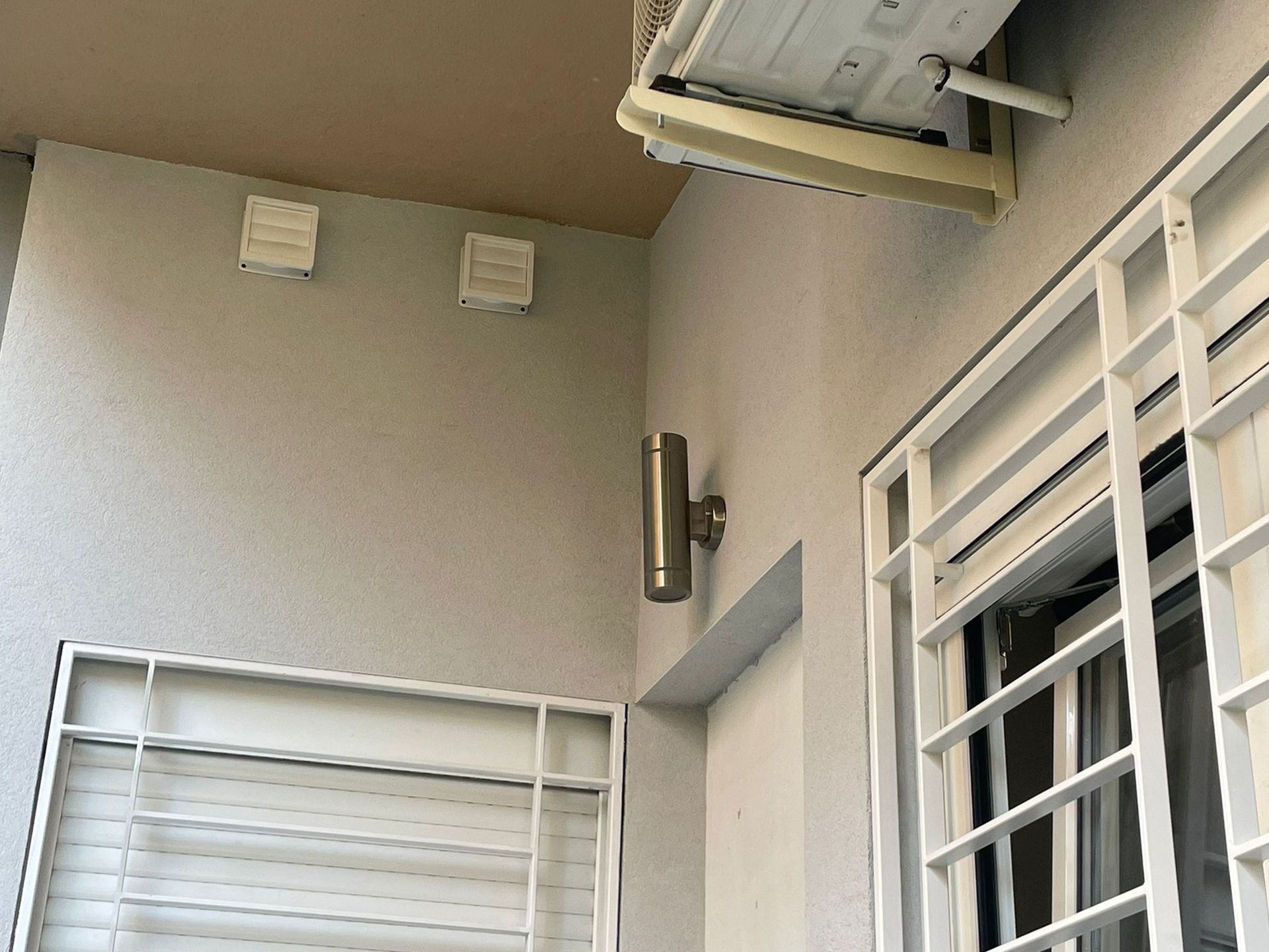 Un balcón con una ventana y un aire acondicionado colgando del techo.
