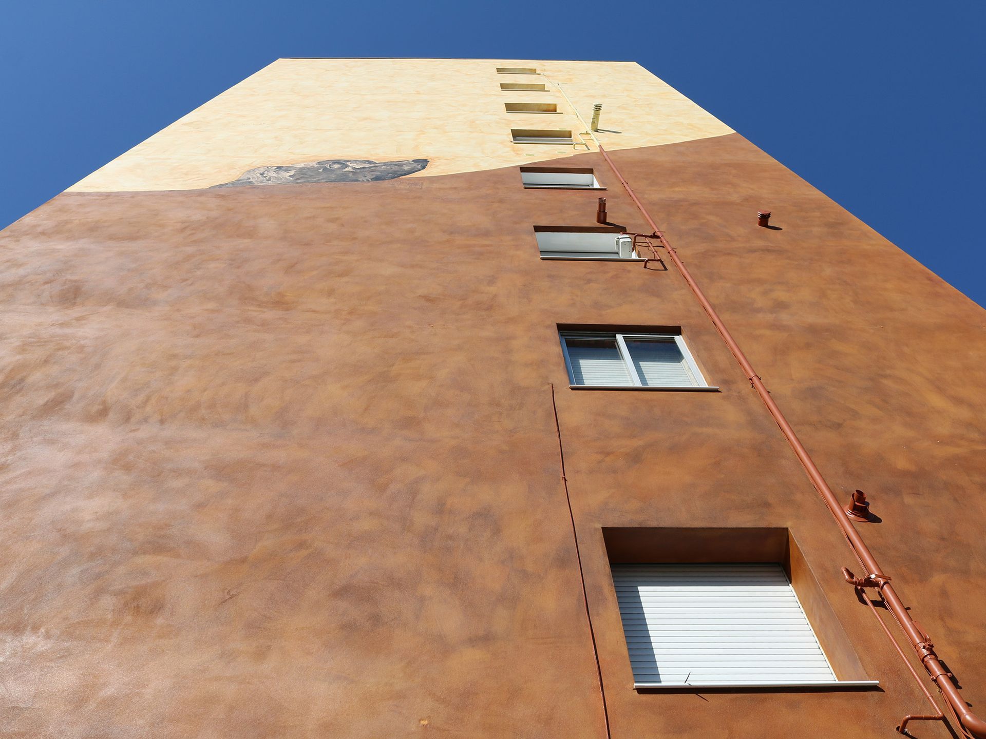 Mirando hacia arriba a un edificio alto con un cielo azul en el fondo