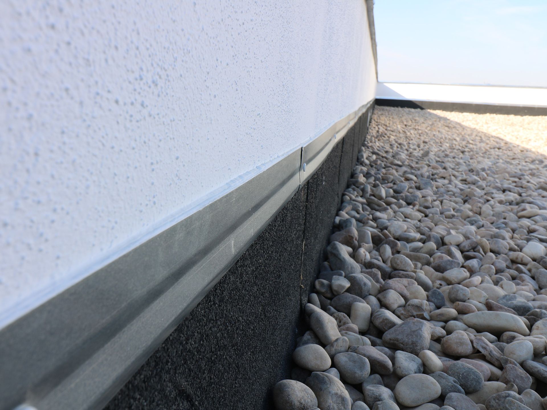 Una pared blanca con un borde negro está rodeada de rocas.