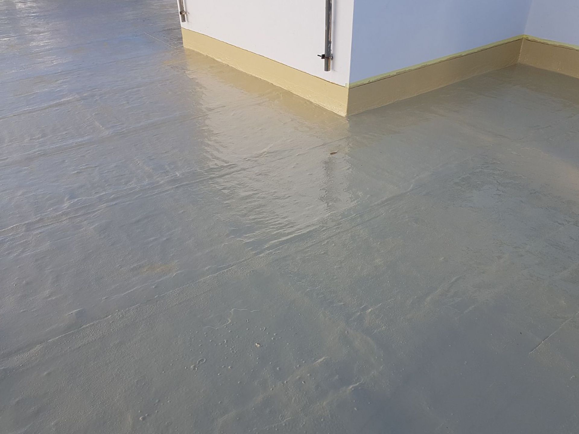 Un primer plano de un piso de concreto con una pared blanca en el fondo.