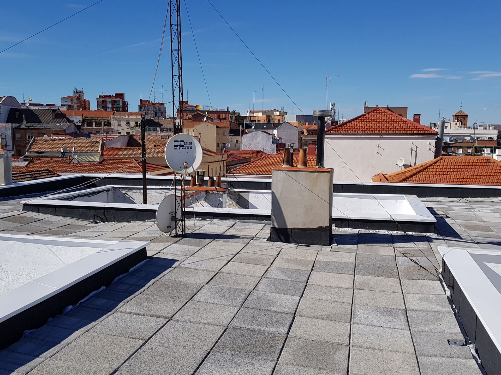 Un tejado con chimenea y antena parabólica.