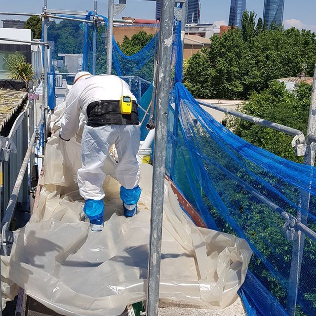 Un hombre está de pie sobre un andamio cubierto de plástico.