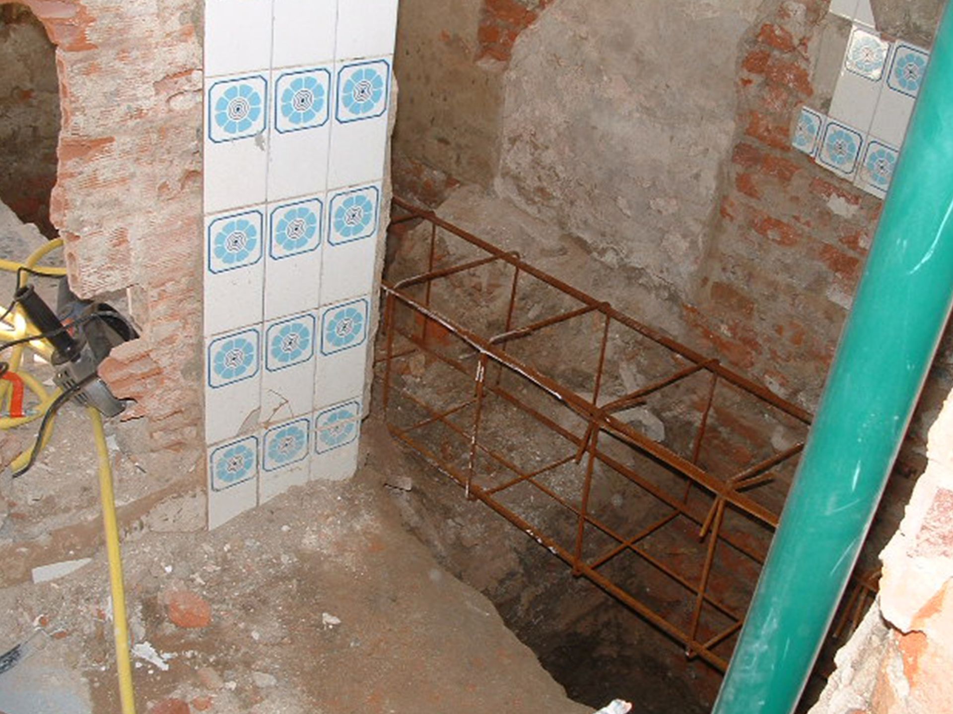 Una pared de ladrillos con azulejos azules y blancos y una tubería verde.