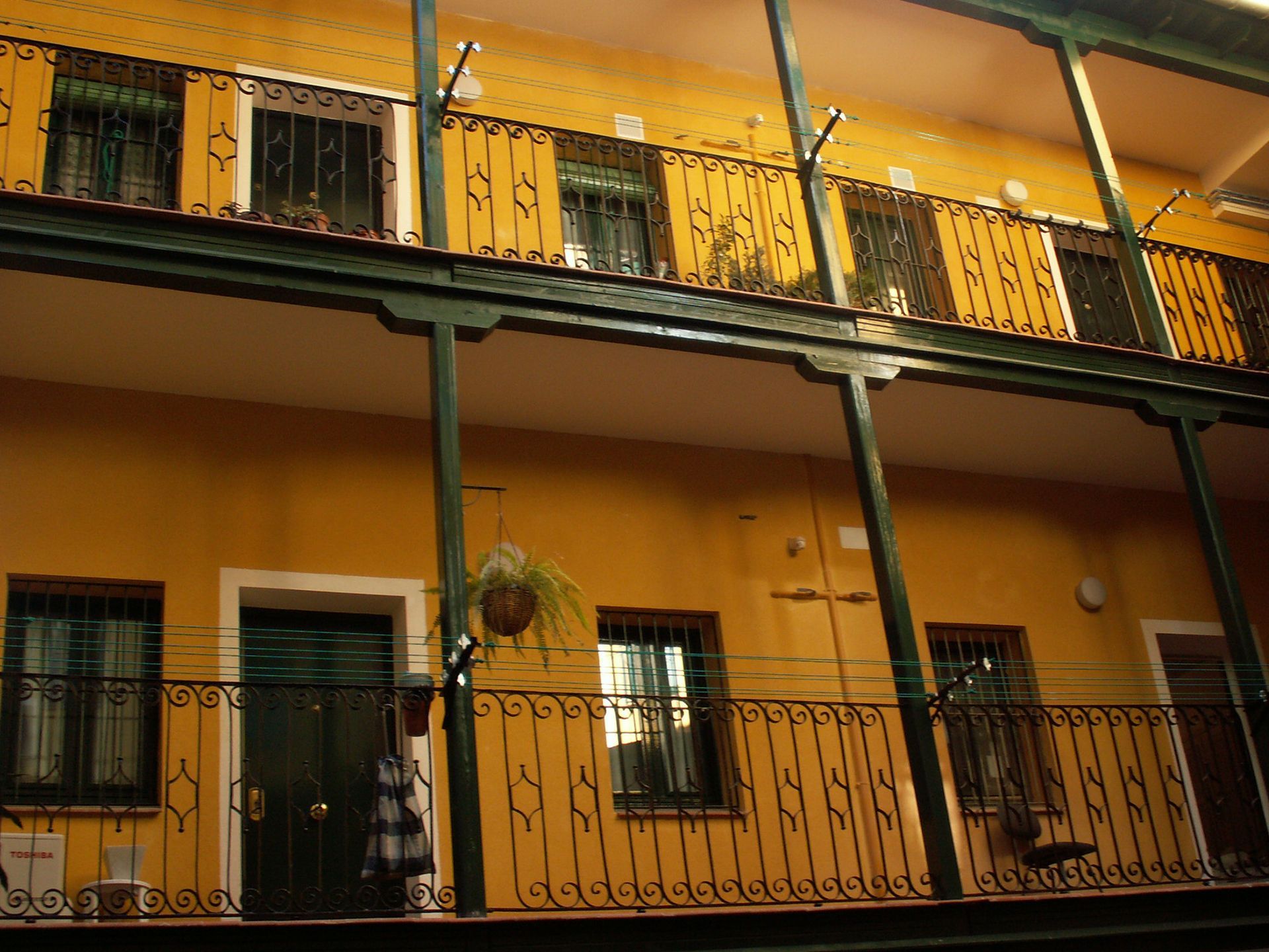 Un edificio amarillo con un balcón y una barandilla verde.