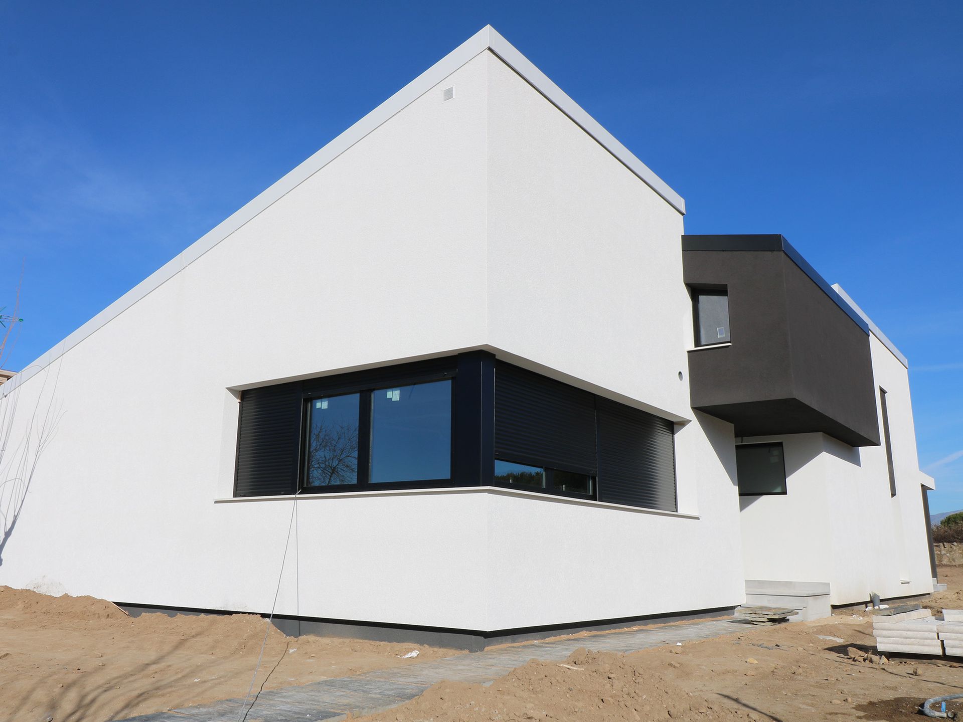 Un edificio blanco con ventanas negras y un cielo azul al fondo.