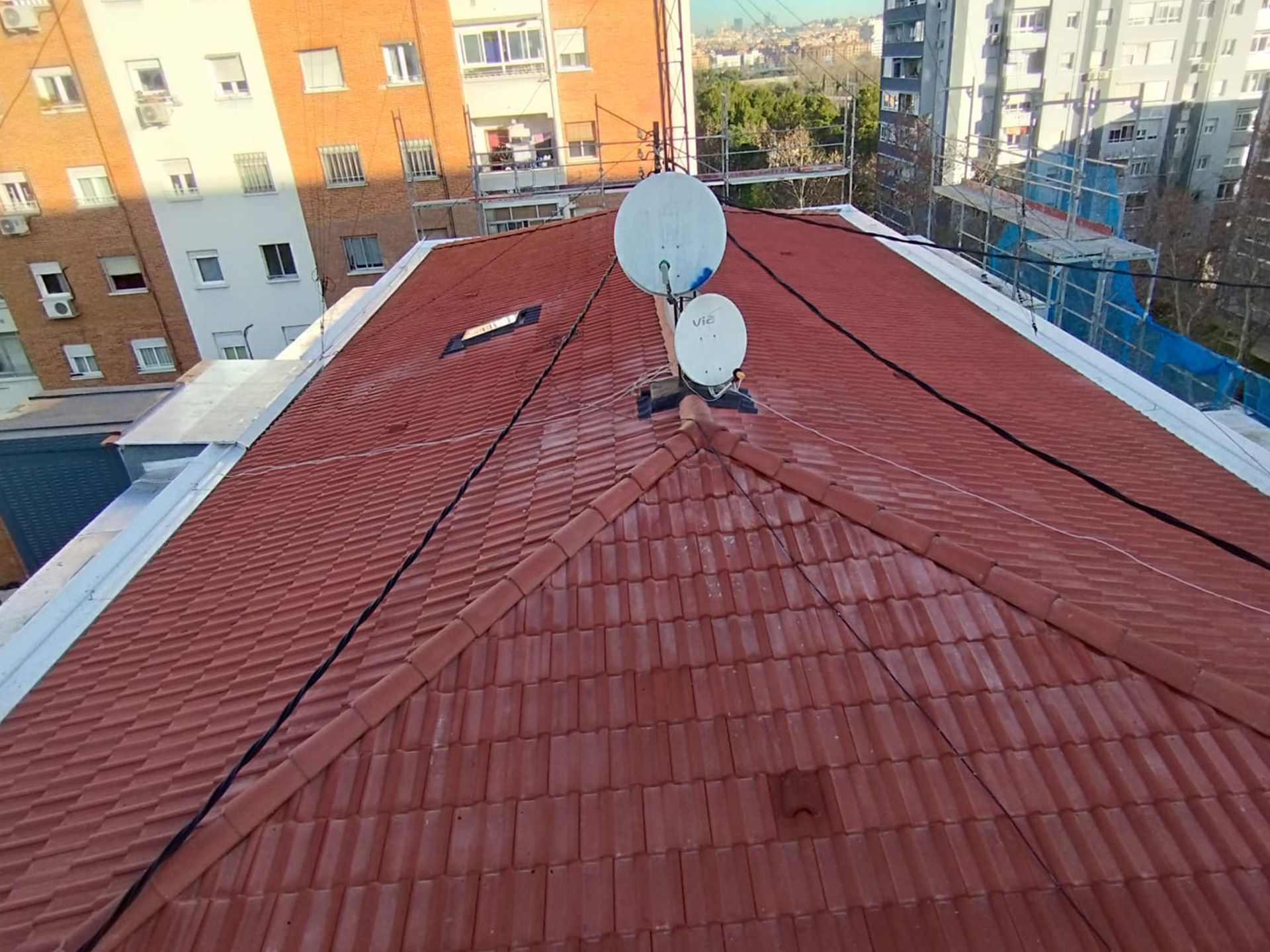 Un techo de tejas rojas con dos antenas parabólicas.