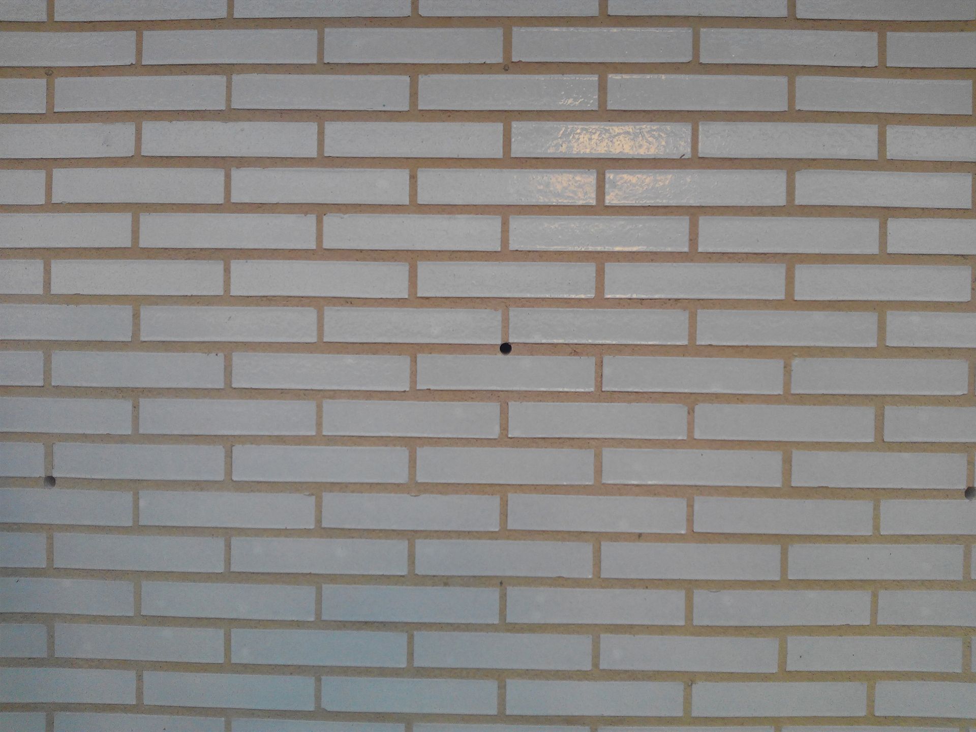 Un primer plano de una pared de ladrillo blanco con algunos agujeros.