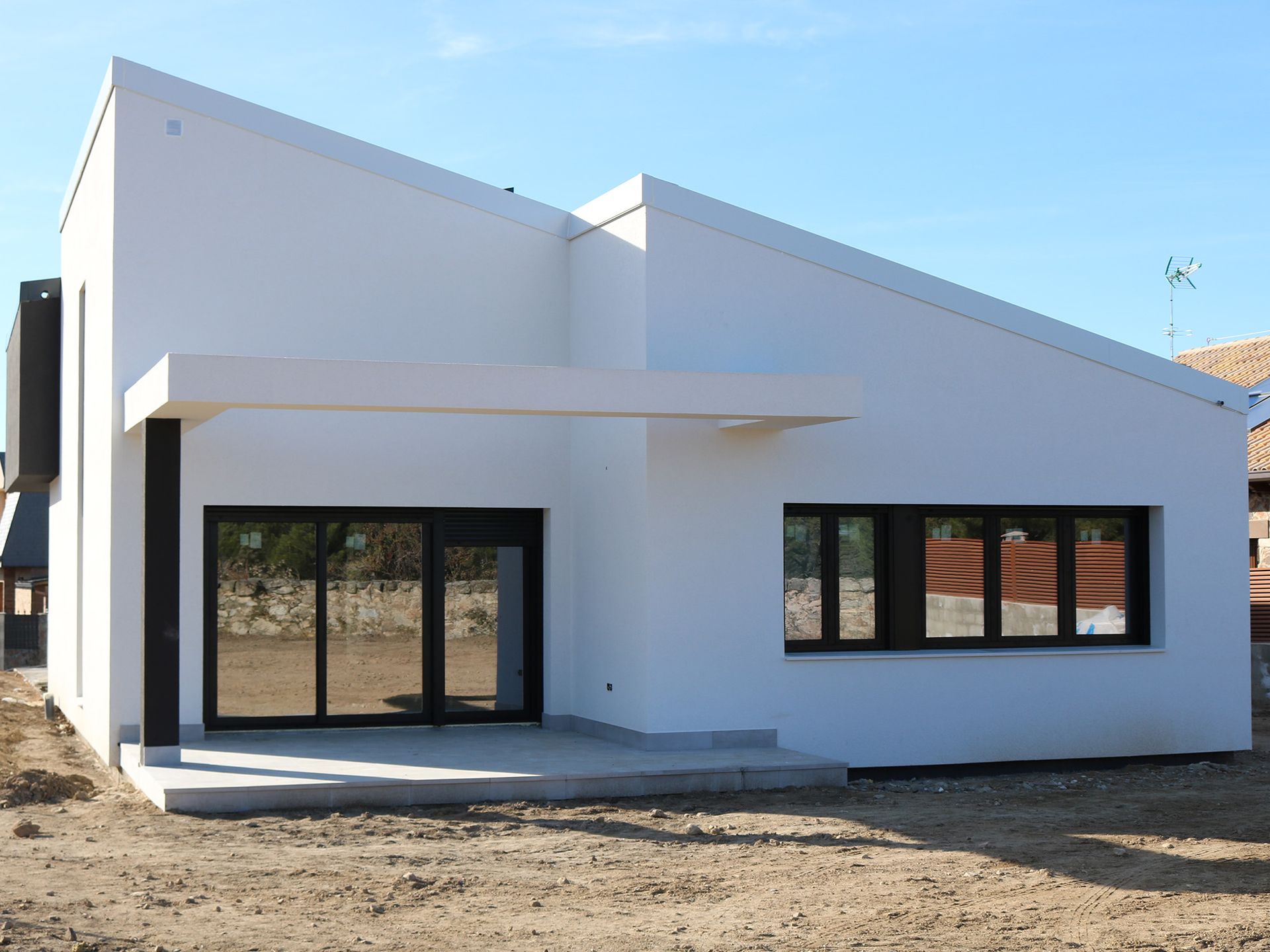 Una casa blanca con ventanas negras está sentada en el suelo.