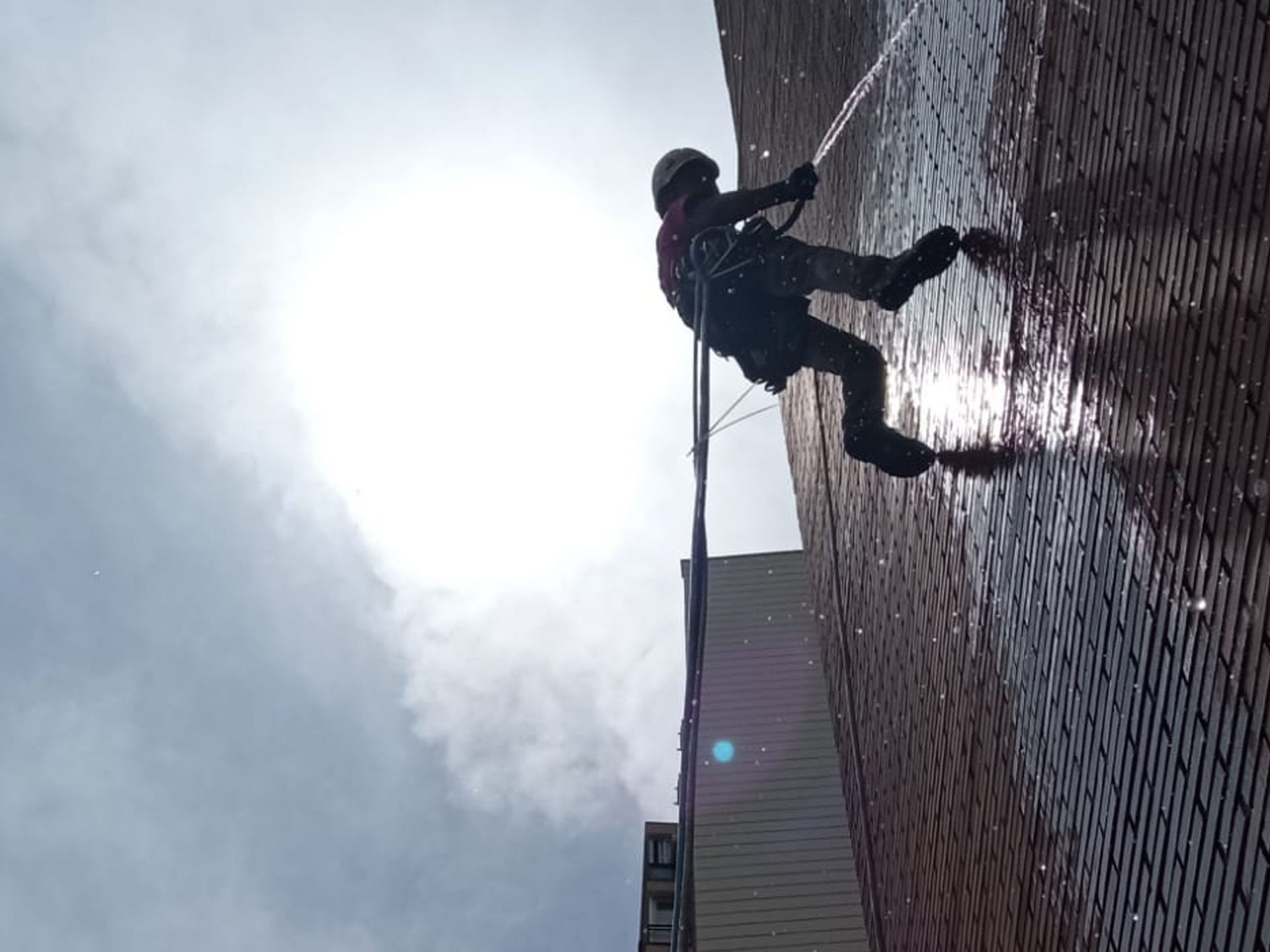 Un hombre está limpiando una pared de ladrillos con una manguera.
