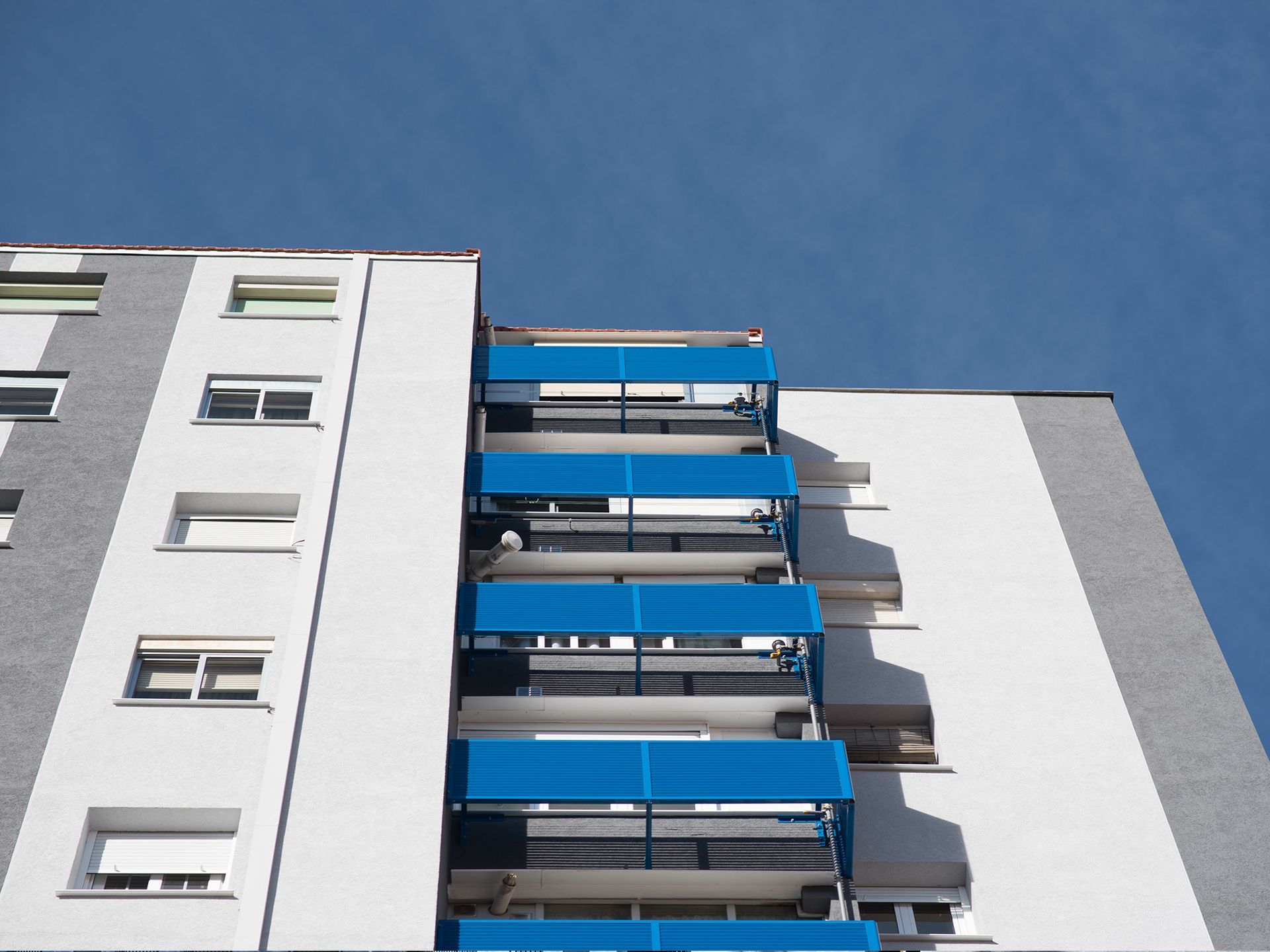 Mirando hacia arriba a un edificio alto con balcones azules