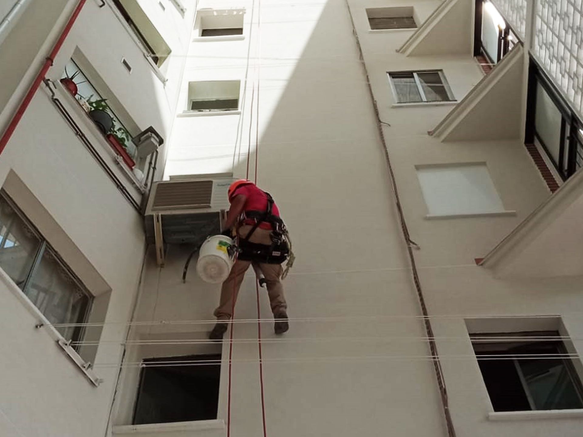 Un hombre está subiendo a un edificio con un cubo en la mano.