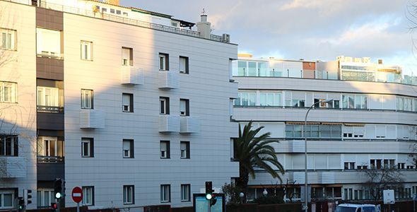 Un edificio blanco con una palmera delante.