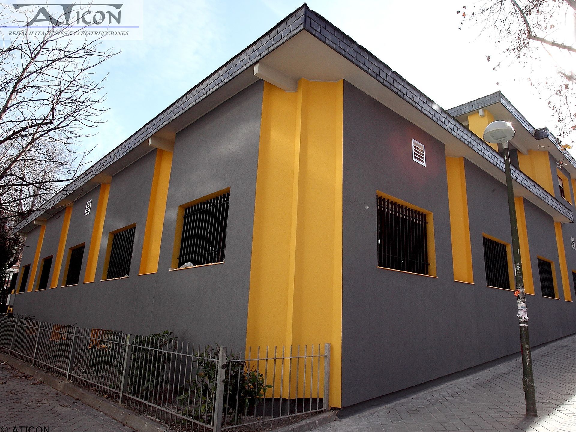 Un edificio amarillo y gris con un cartel que dice Aikon.